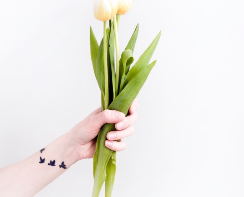 hand holding tulips with tattoo